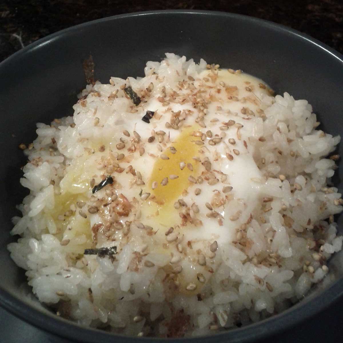 A bowl of rice topped with partially-cooked egg and furikake (Japanese condiment).